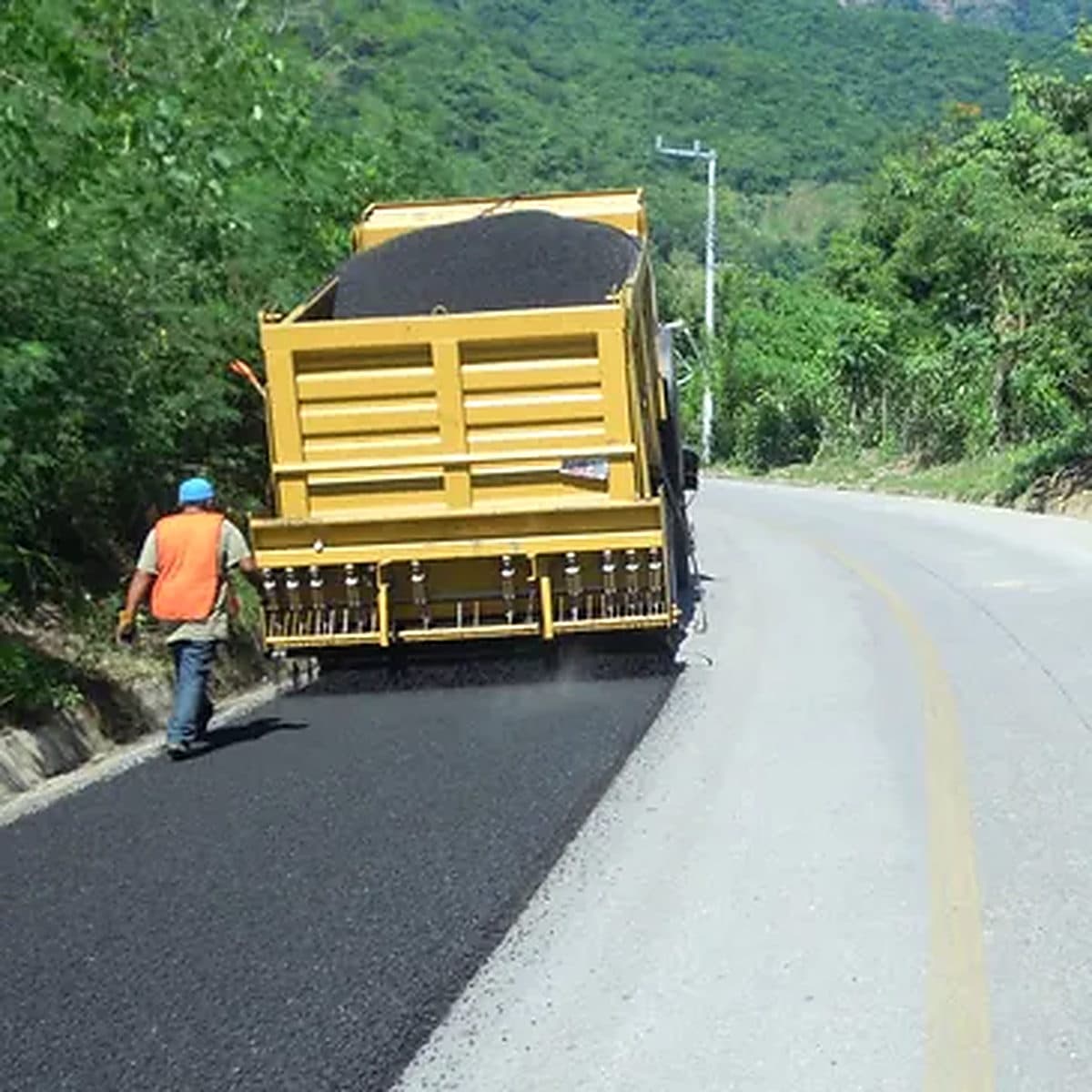 Camión esparciendo sello premezclado sobre una carretera